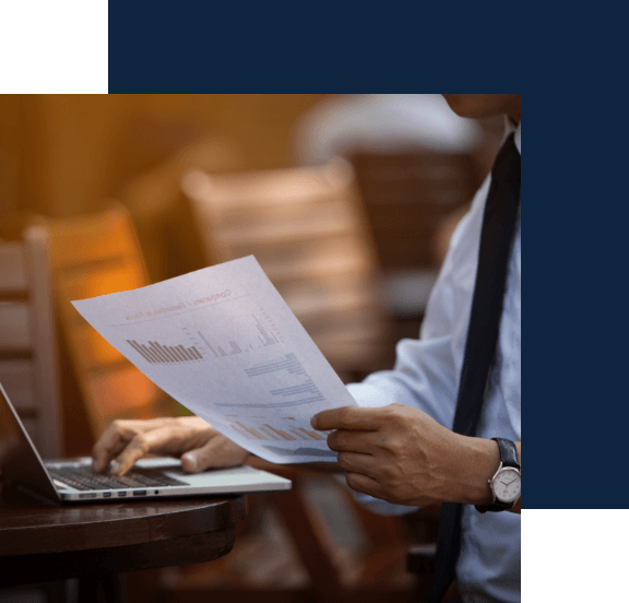 A man reviewing a document with his laptop open.